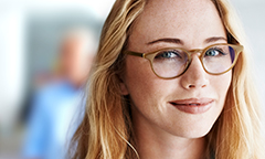 Young woman with long hair and glasses with blurry people in the background